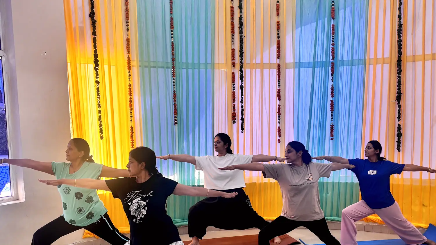 A Living Yog group class practising virabhadrasana together in the Palam Vihar studio