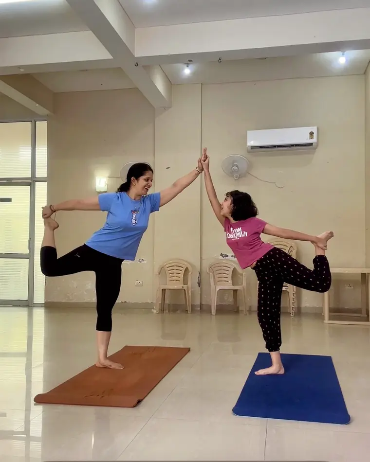 An adult and a child practising vrksasana together